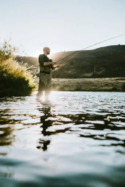 A man fly fishing on the Deschutes river in Warm Springs, Oregon, fishing for trout.