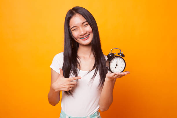 istock Young Asian woman point to a clock. 1043837760