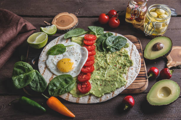 istock tortilla with guacamole avocado, fried egg and tomato, spinach leaves. vegetarian dish 1043844656
