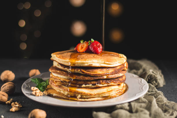 istock American pancakes with walnuts and strawberry topped with maple syrup. 1043845352