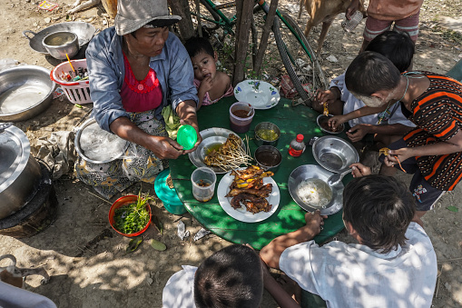 Ethnic street children and poor people having lunch on street in Yangon, Myanmar. There are many street children and poor people in Yangon.