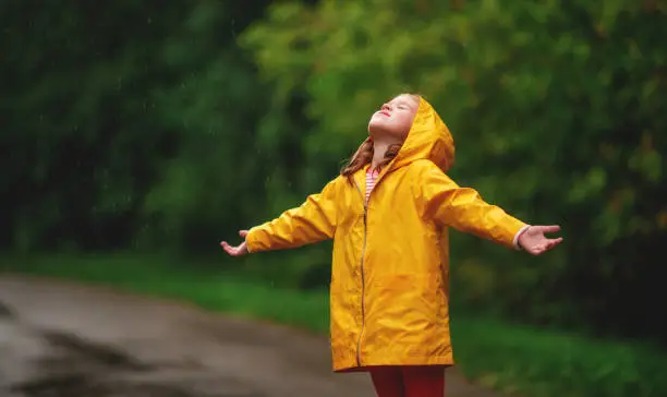 Photo of happy child girl enjoying autumn rain