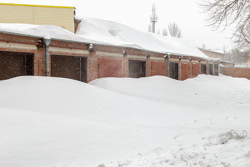 Huge snow banks near garage doors in winter during blizzard