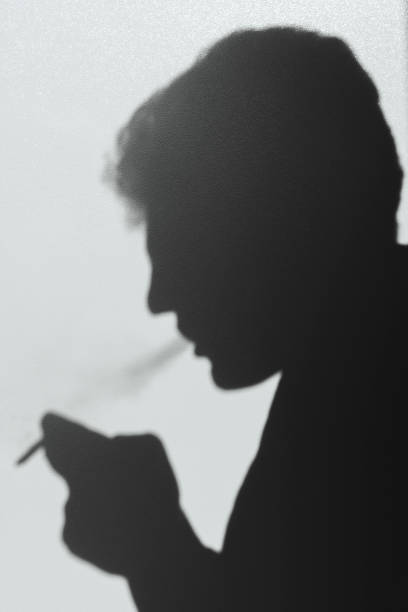istock shadow of smoking man, young man smoking a cigarette, concept abstract background 1043878438