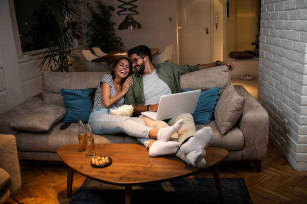 joven pareja viendo una película en un ordenador portátil. - comfortable relaxation sofa men fotografías e imágenes de stock