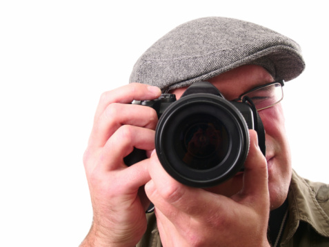 Photographer with a camera isolated on white. Focus is on the lens.