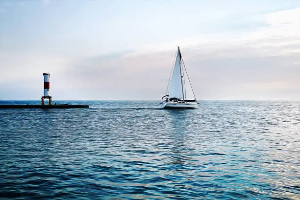 Photo of Yacht and Lighthouse at the sunset in the blue sea. Oil Painting Background.