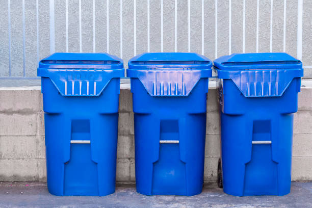Blue garbage cans againts a fence