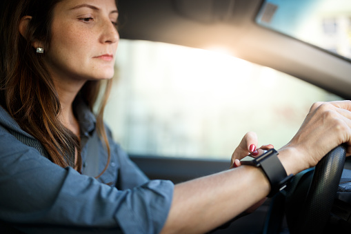 woman checking her smartwatch while the traffic is stopped.
