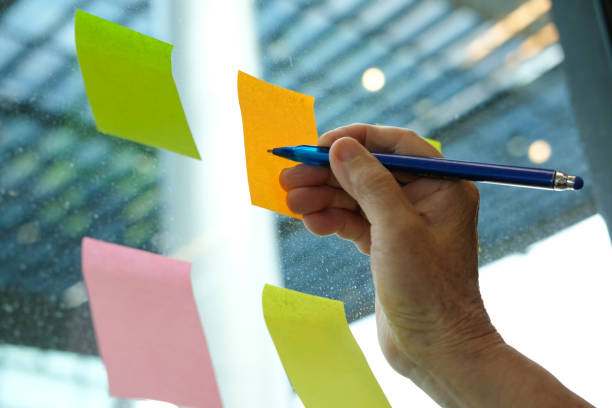istock hand write on adhesive notes on glass wall. Sticky note paper reminder schedule for discussing creative idea & business brainstorming 1043927326
