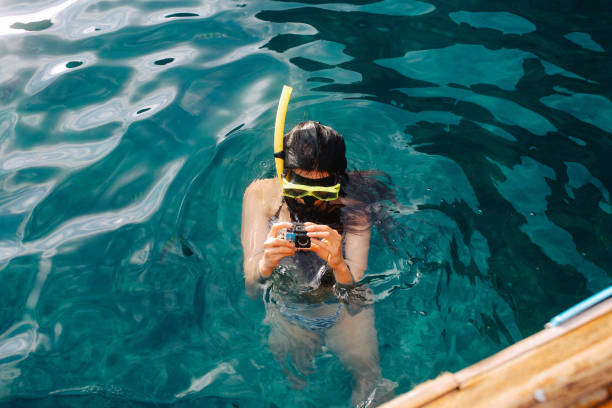istock Young woman setting up her action camera for snorkeling 1043933358