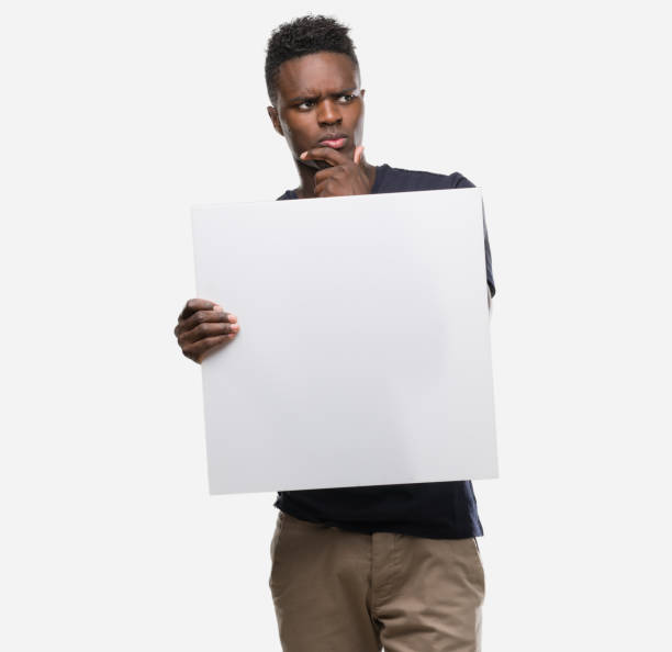 istock Young african american man holding a banner serious face thinking about question, very confused idea 1043958632