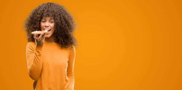 istock African american woman with a pizza slice with a confident expression on smart face thinking serious 1043972092