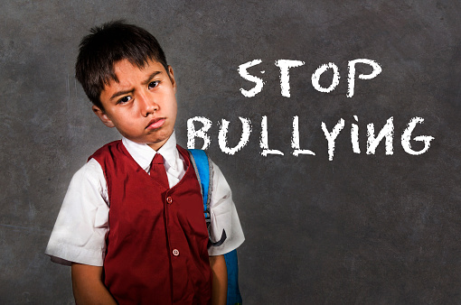 dramatic portrait of young desperate and abused schoolboy screaming and crying victim of bullying and abuse at school isolated on blackboard background in bullied kid social problem