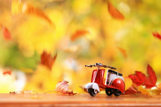 Autumn scene of a scooter surounded by falling leaves