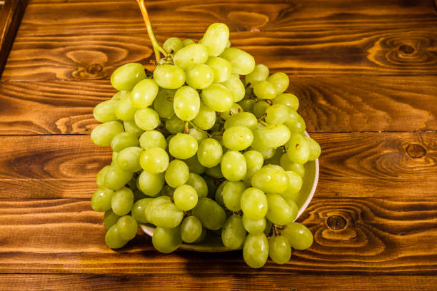 istock Ceramic plate with green grapes on wooden table 1044006144