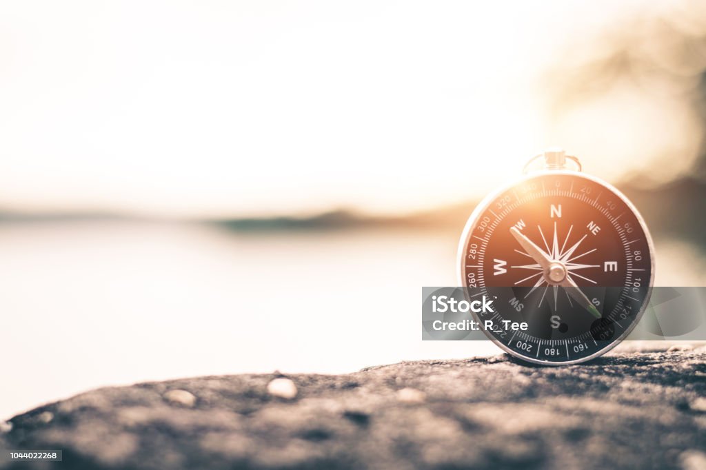 Compass of tourists on mountain at sunset sky. Navigational Compass Stock Photo