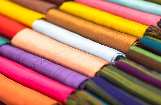 Rolls of different colored fabrics at a fabric store.