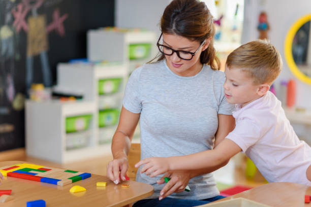 istock Kindergarten Teacher Supports Cute Boy in Educational Game Play 1044043232
