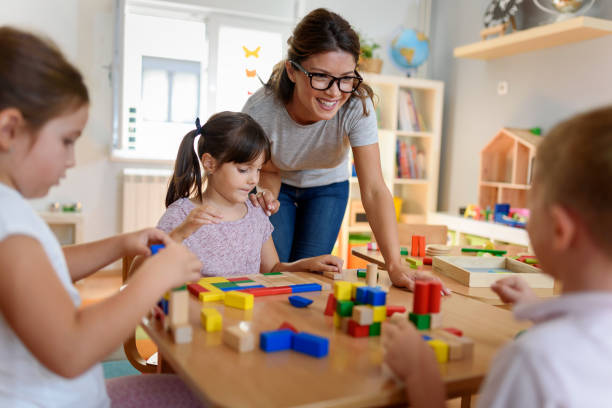 Preschool teacher with children playing with didactic toys Preschool teacher with children playing with colorful wooden didactic toys at kindergarten preschool student stock pictures, royalty-free photos & images