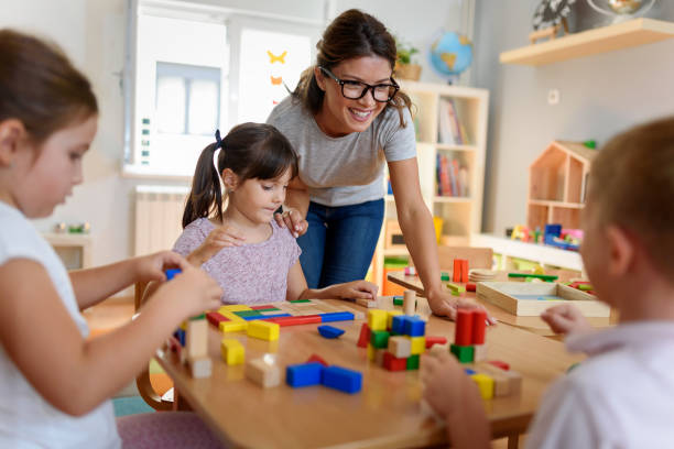 Preschool teacher with children playing with didactic toys Preschool teacher with children playing with colorful wooden didactic toys at kindergarten preschool classroom jobs stock pictures, royalty-free photos & images