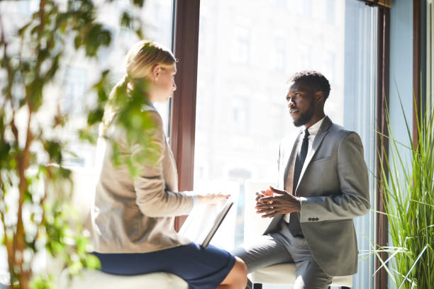 istock Serious business lady with clipboard interviewing black bearded manager who explaining his project plan 1044046862