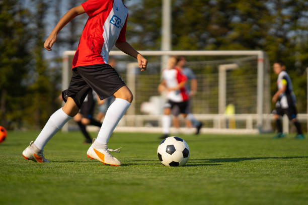 istock junior soccer player with football during match 1044058648
