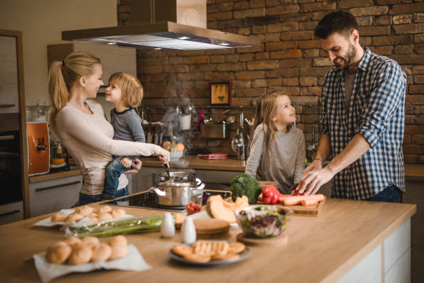 istock Young smiling parents enjoying while preparing lunch with their kids in the kitchen. 1044058712