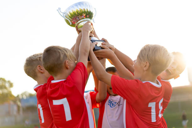 istock successful young soccer team celebrating trophy in sunlight 1044058752