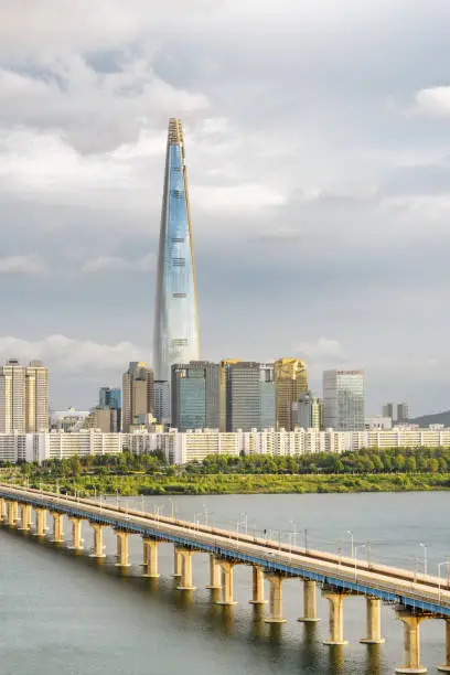 Scenic view of modern tower and Jamsil Railway Bridge over the Han River (Hangang) at downtown of Seoul in South Korea. Amazing skyscraper is visible on cloudy sky background. Wonderful cityscape.
