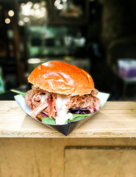 Freshly flame grilled pulled pork burger on wooden counter at food market