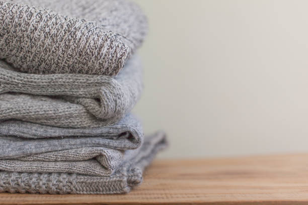 istock Stack of cozy grey sweaters for cold autumn on wooden table. 1044066676