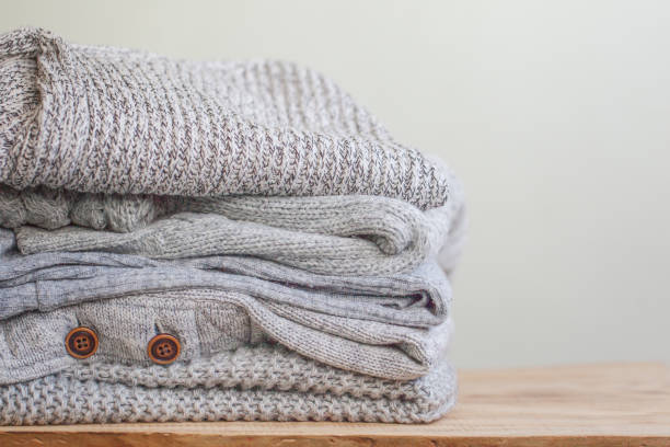 istock Stack of cozy grey sweaters for cold autumn on wooden table. 1044066684