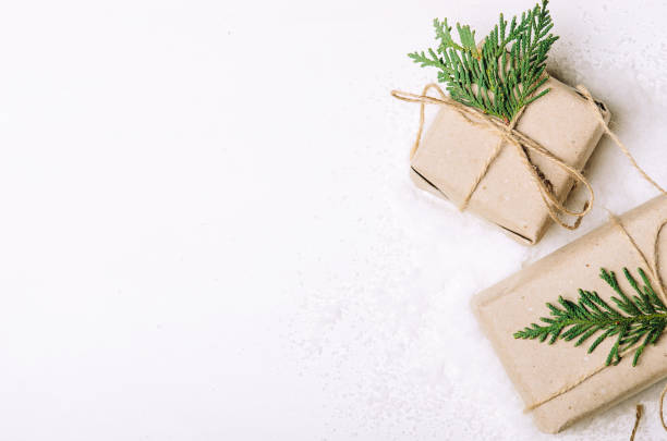 istock Gift boxes in kraft paper and fir branches on white background and artful snow. Rustic style. Copy Space, flat lay. 1044071002