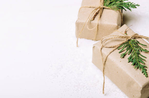 istock Gift boxes in kraft paper and fir branches on white background and artful snow. Rustic style. Copy Space 1044071006