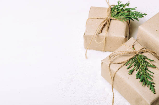 istock Gift boxes in kraft paper and fir branches on white background and artful snow. Rustic style. Copy Space 1044071010