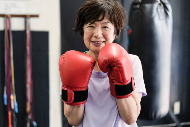 Senior adult women training at boxing gym Japanese senior adult women training with male instructor at boxing gym old man boxing stock pictures, royalty-free photos & images