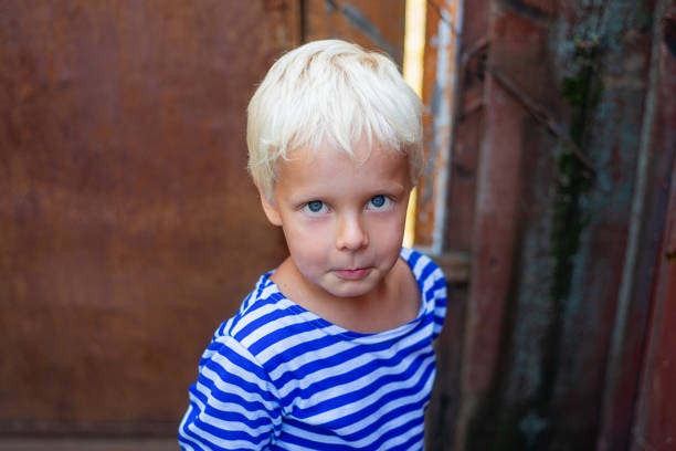 garçon blond regarde la caméra avec un regard coupable. portrait d’un enfant blond - child blank expression pensive focus on foreground photos et images de collection