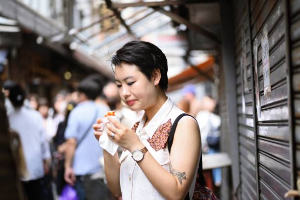 jeune femme manger des fruits de mer au marché aux poissons - tattoo japanese culture women asian ethnicity photos et images de collection