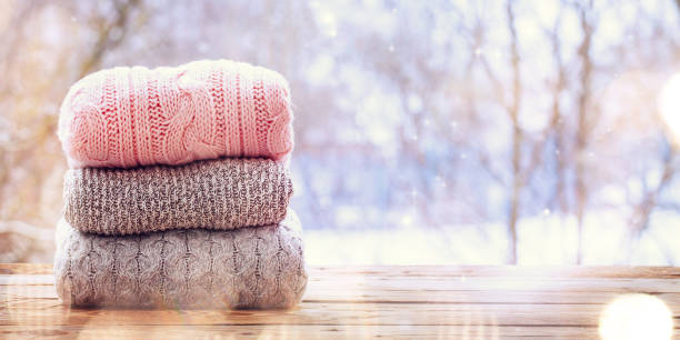 istock Banner. Still life with Stack of wool knitted sweaters on wooden table on winter nature background. 1044090210