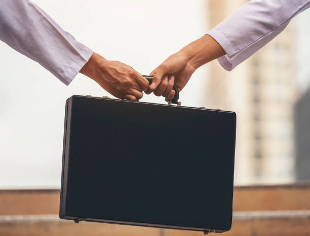 istock Cropped Hands Of People Holding Black Briefcase 1044090294