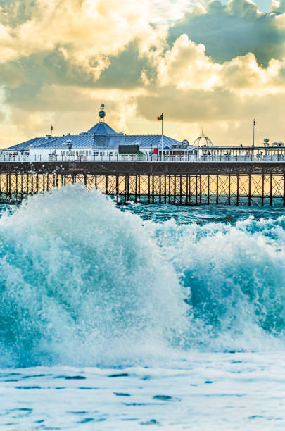 Brighton Pier, Brighton, Sussex, Britain on a stormy evening at dusk as the sun is setting. There are high waves and surf on the beach Brighton Pier, Brighton, Sussex, Britain on a stormy evening at dusk as the sun is setting. There are high waves and surf on the beach brighton england stock pictures, royalty-free photos & images
