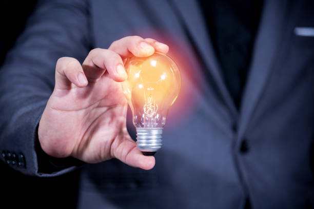 istock Midsection Of Businessman Holding Illuminated Light Bulb 1044109628