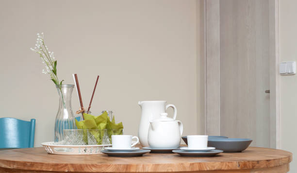 istock Modern interior with wooden table, plates cups and vase with flowers 1044110338