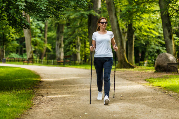 Mid aged woman nordic walking in city park People nordic walking in city park nordic walking pole stock pictures, royalty-free photos & images