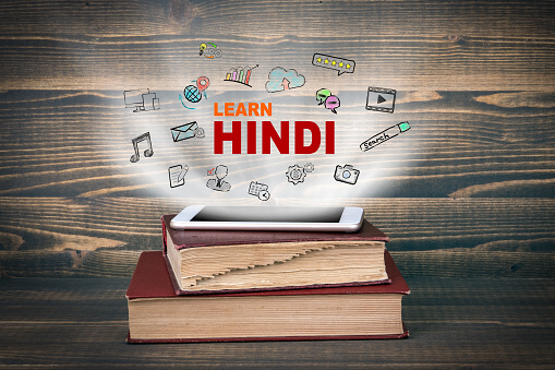 learn Hindi, education and business background. Concept cloud coming from screen of the phone, books on the desk