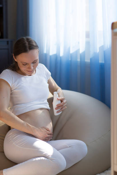 istock Young pregnant lady is putting cream on her belly 1044124938