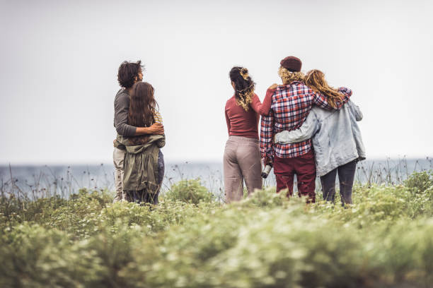 Back view of embraced people looking at sea view.