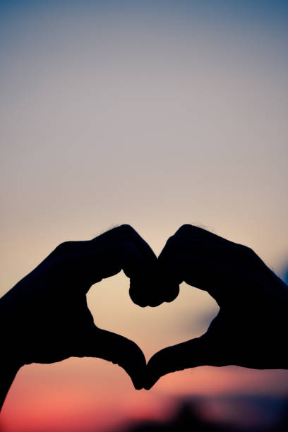istock Love sign. Heart symbol by hand silhouette in sunset sky. Vintage style. 1044136708