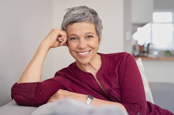 gelukkig senior vrouw op bank - woman smiling stockfoto's en -beelden